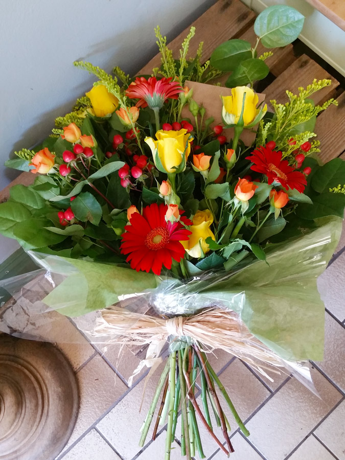 Forward-facing, handtied sheaf - yellow, orange and red gerbera and spray roses