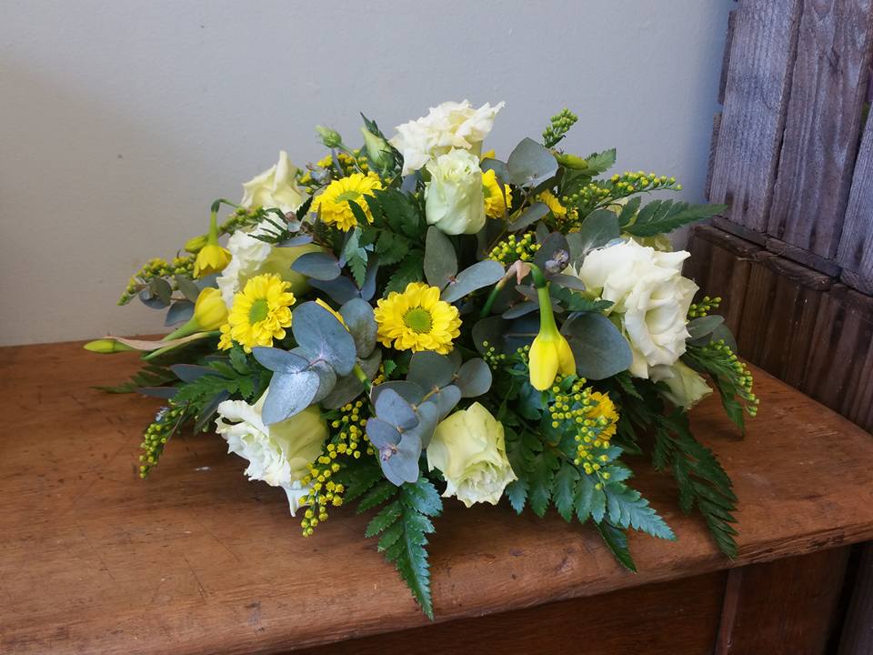 Table flower arrangement with daffodils and white roses