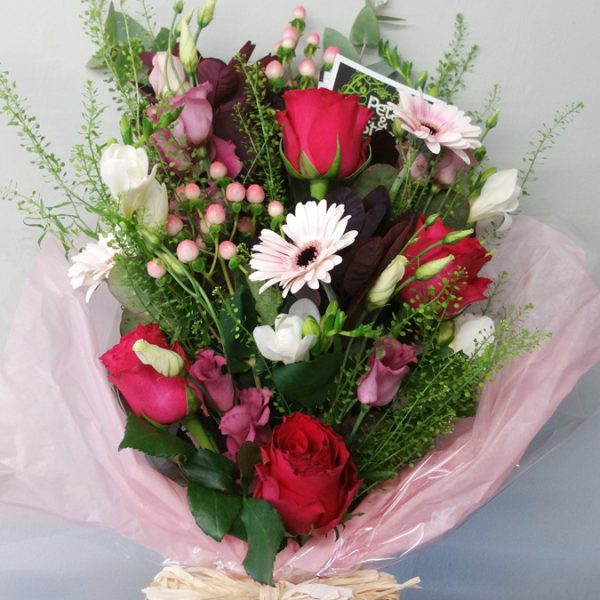 Forward-facing handtied sheaf with red rose, pink gerbera, freesia, lisianthus and berries